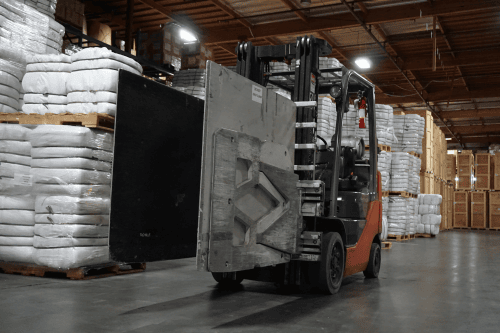 Forklift with clamp attachment handling specialized loads in a warehouse at San Jose Distribution Services